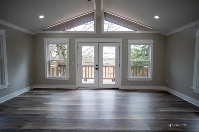 a view of an empty room with wooden floor and a window