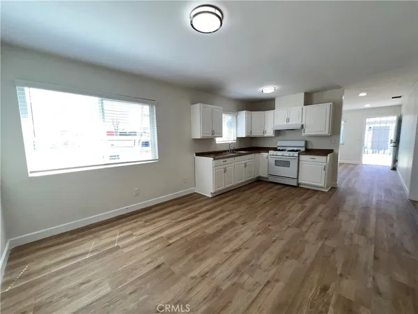 a kitchen with stainless steel appliances granite countertop a stove a sink dishwasher and a oven with white cabinets