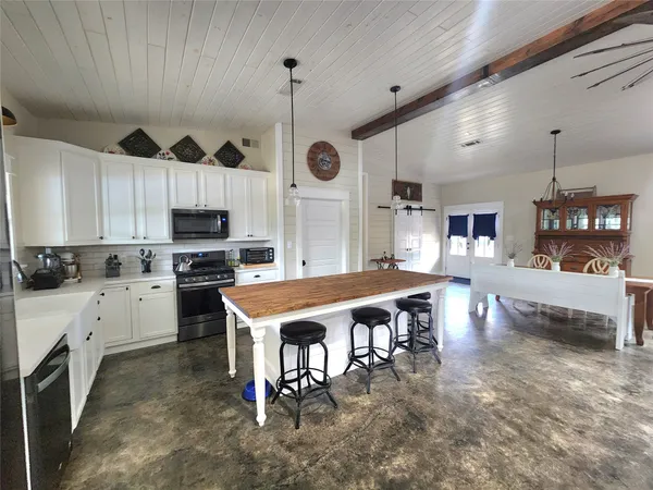 a kitchen with stainless steel appliances granite countertop a stove a sink dishwasher a refrigerator and white cabinets with wooden floor