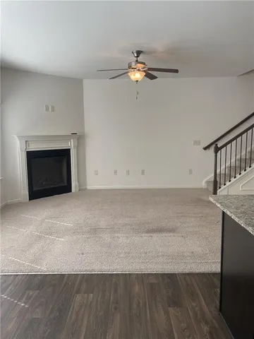 an empty room with wooden floor fireplace and windows