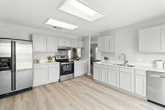 a kitchen with white cabinets and wooden floors
