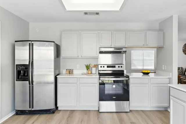 a kitchen with granite countertop white cabinets and stainless steel appliances