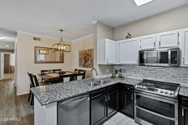 a kitchen with stainless steel appliances granite countertop a refrigerator a stove top oven a sink and dishwasher