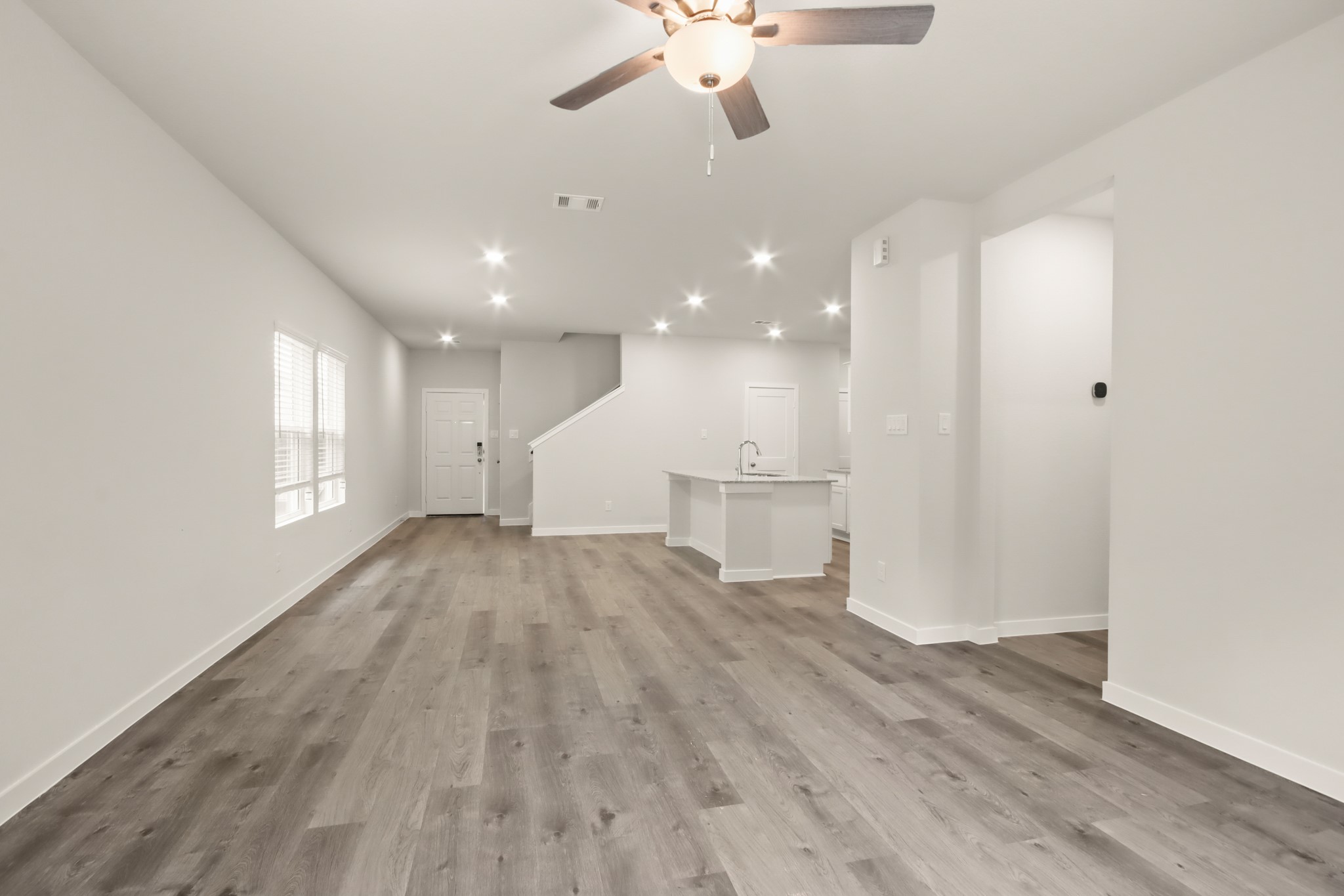 16922 Needlepoint Drive Conroe, TX 77302 - Photo 8 of 31 an empty room with wooden floor ceiling fan and windows