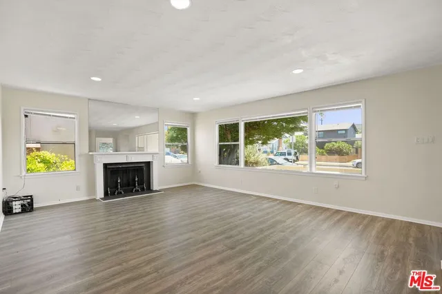 an empty room with wooden floor fireplace and windows