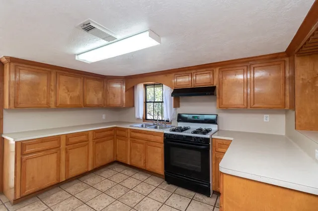 a kitchen with stainless steel appliances granite countertop stove top oven sink and cabinets