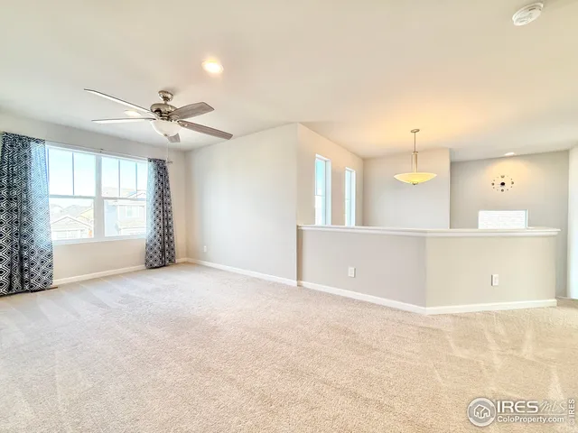 an empty room with windows and ceiling fan