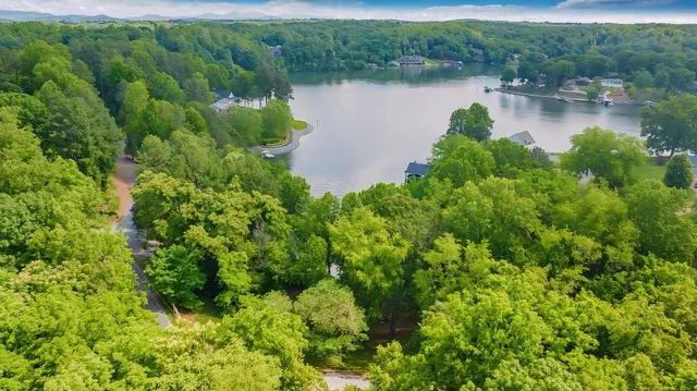 an aerial view of lake residential house with outdoor space and trees all around