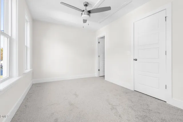 an empty room with a ceiling fan and a window