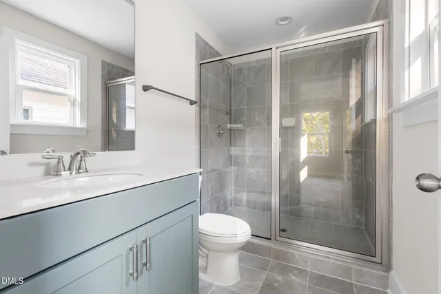 a bathroom with a shower sink vanity mirror and toilet