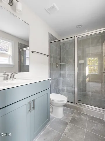 a bathroom with a shower sink vanity mirror and toilet