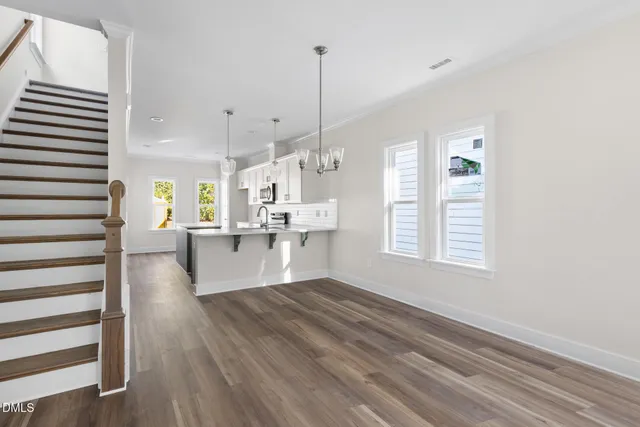 a large white kitchen with kitchen island a stove a chimney wooden floor and a window