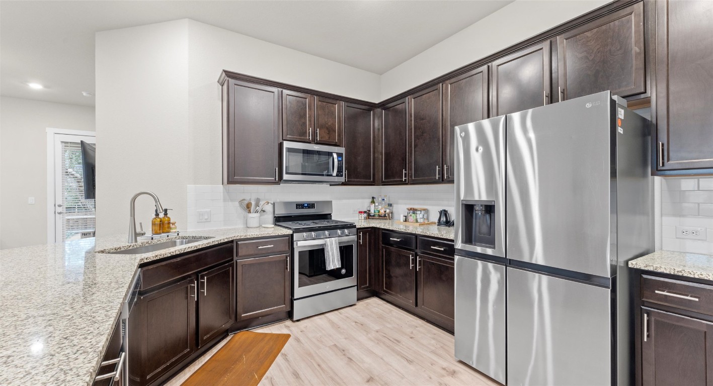 2416 Bear Cub Bend Leander, TX 78641 - Photo 7 of 24 a kitchen with stainless steel appliances granite countertop a refrigerator stove microwave and sink