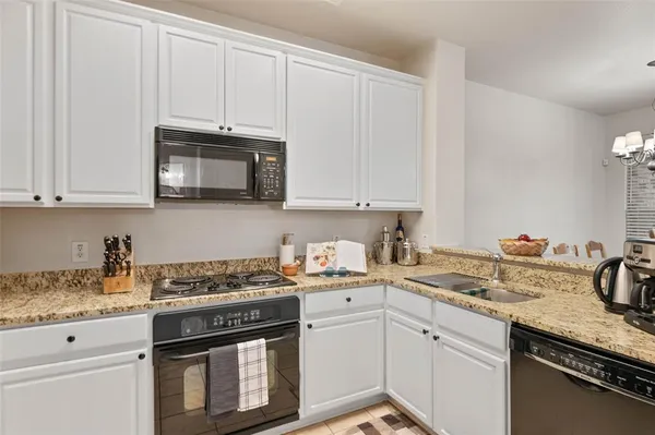 a kitchen with stainless steel appliances granite countertop a refrigerator stove and white cabinets