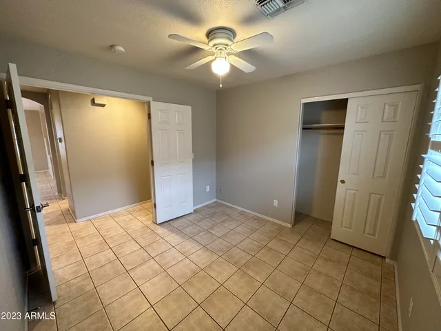 an empty room with closet and a chandelier fan