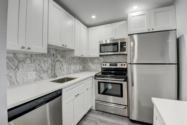 a kitchen with stainless steel appliances white cabinets and a refrigerator