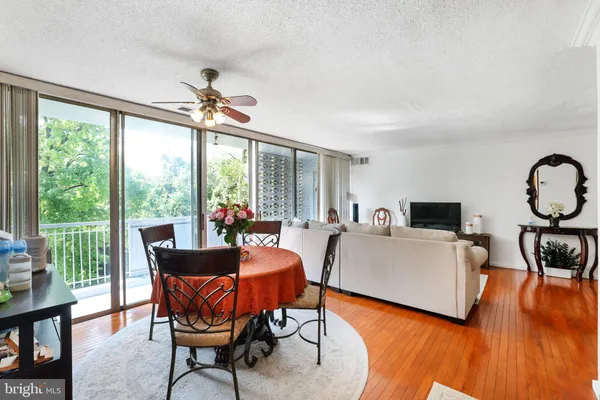 a living room with furniture a ceiling fan and a large window