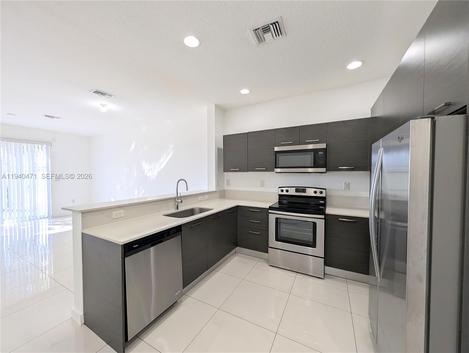 3484 Northwest 13th Street, Unit 3484 Lauderhill, FL 33311 - Photo 3 of 49 a kitchen with stainless steel appliances granite countertop a sink stove and refrigerator