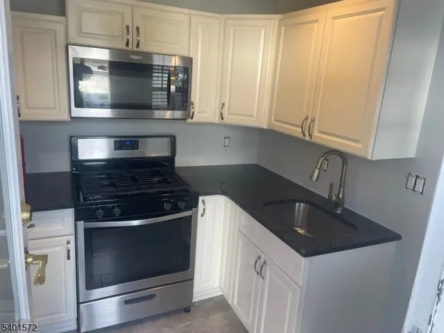 a kitchen with granite countertop white cabinets stainless steel appliances and sink