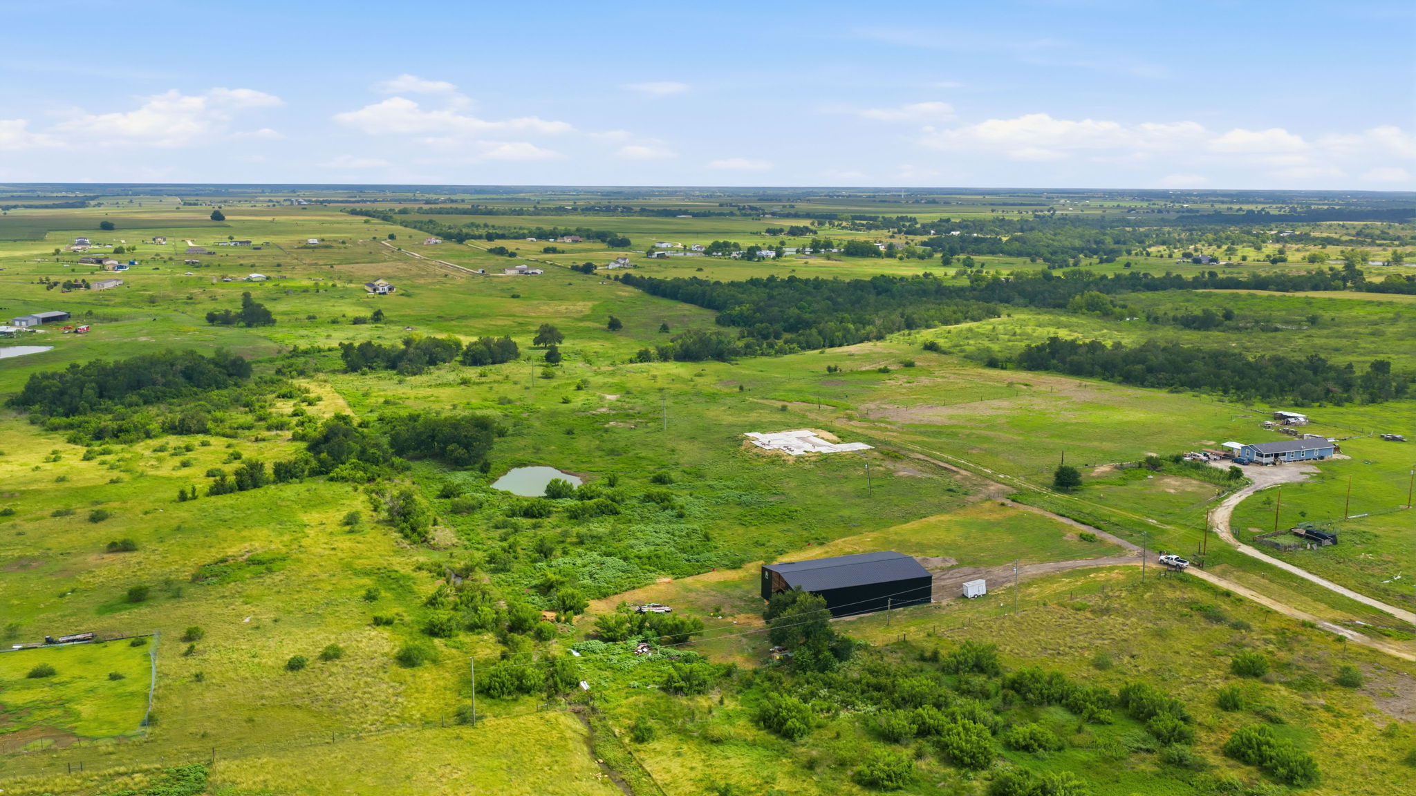1701 County Road 466 Elgin, TX 78621 - Photo 20 of 24 Vast green acreage featuring diverse terrain, scattered residences, and multiple ponds under an open sky.