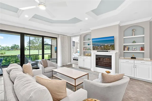 a living room with furniture large window and kitchen view