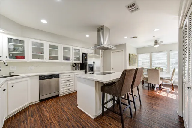 a kitchen with a table chairs wooden floors and white cabinets