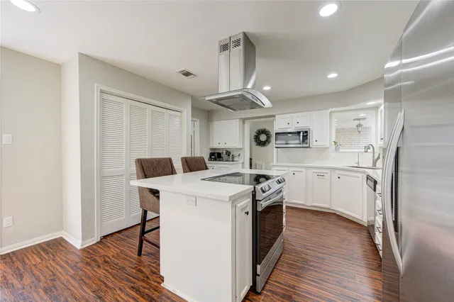 a kitchen with a sink a stove a refrigerator and white cabinets with wooden floor