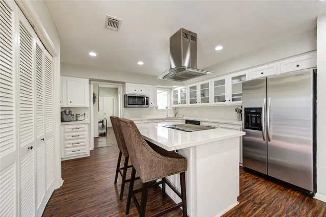 a kitchen with stainless steel appliances a stove a sink a refrigerator cabinets and a dining table