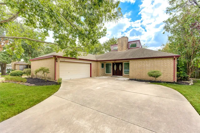 a front view of a house with a garden and trees