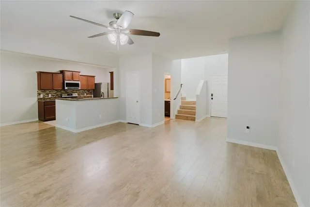 a view of a kitchen with a stove cabinets a ceiling fan and wooden floor