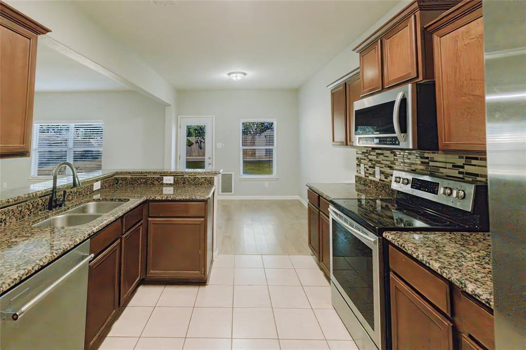 12637 Forest Lawn Road Rhome, TX 76078 - Photo 13 of 31 a kitchen with stainless steel appliances granite countertop a stove microwave and sink