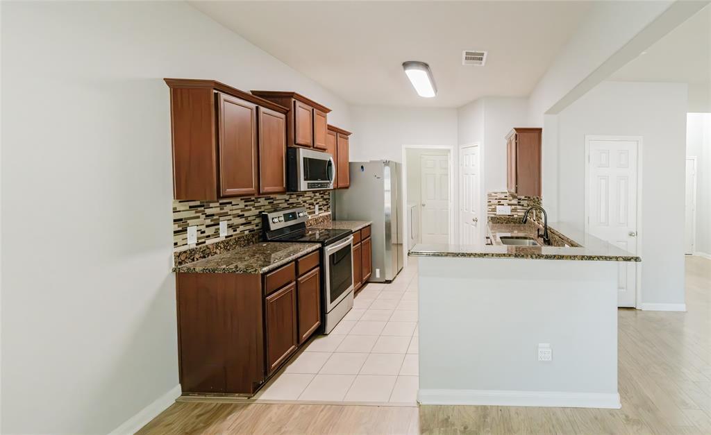 12637 Forest Lawn Road Rhome, TX 76078 - Photo 16 of 31 a kitchen with stainless steel appliances granite countertop a stove a sink and a refrigerator
