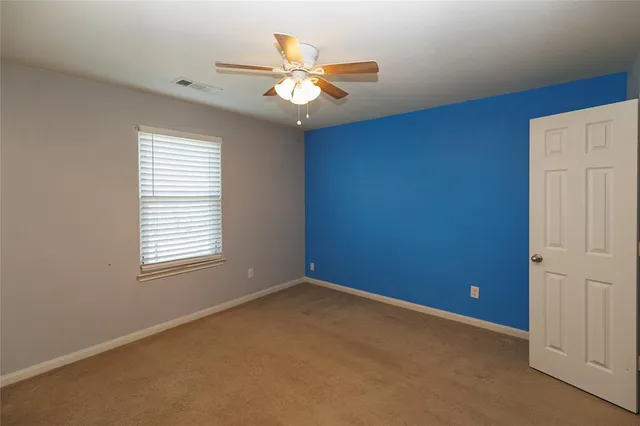 an empty room with a chandelier fan and windows
