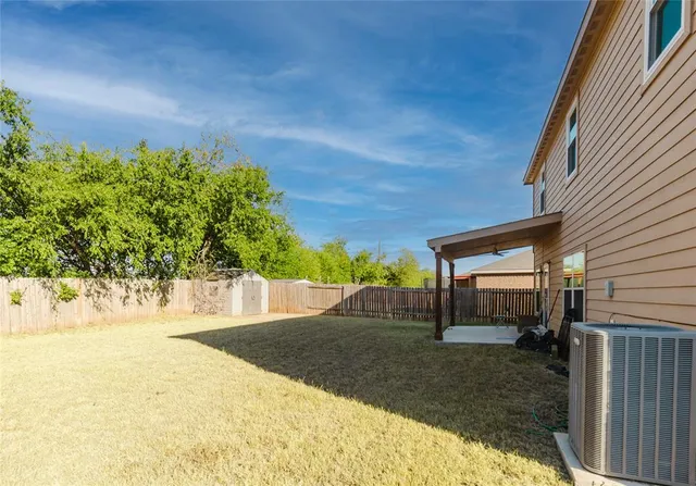 a view of yellow house with a small yard and wooden fence