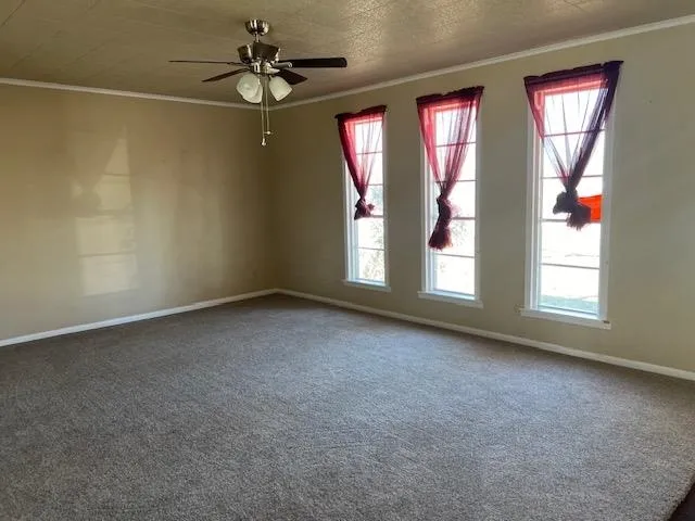 an empty room with windows and chandelier fan