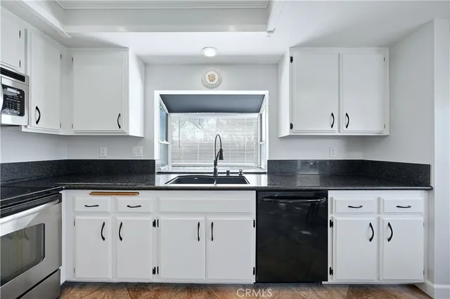 a kitchen with granite countertop white cabinets and black appliances