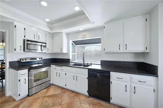 a kitchen with granite countertop white cabinets and white appliances