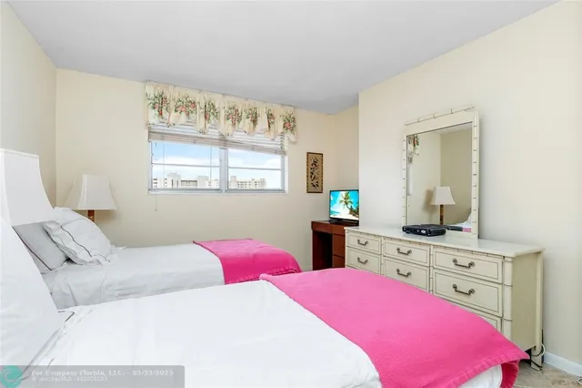 a bedroom with a bed a chandelier and a flat tv screen on dresser