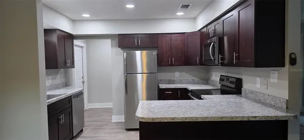 a kitchen with granite countertop kitchen island stainless steel appliances a refrigerator and a counter top space
