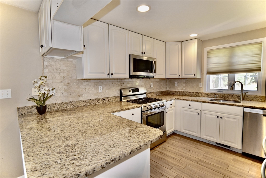 172 Edgehill Road, Unit 172 Norwood, MA 02062 - Photo 4 of 28 a kitchen with granite countertop a sink stove and microwave