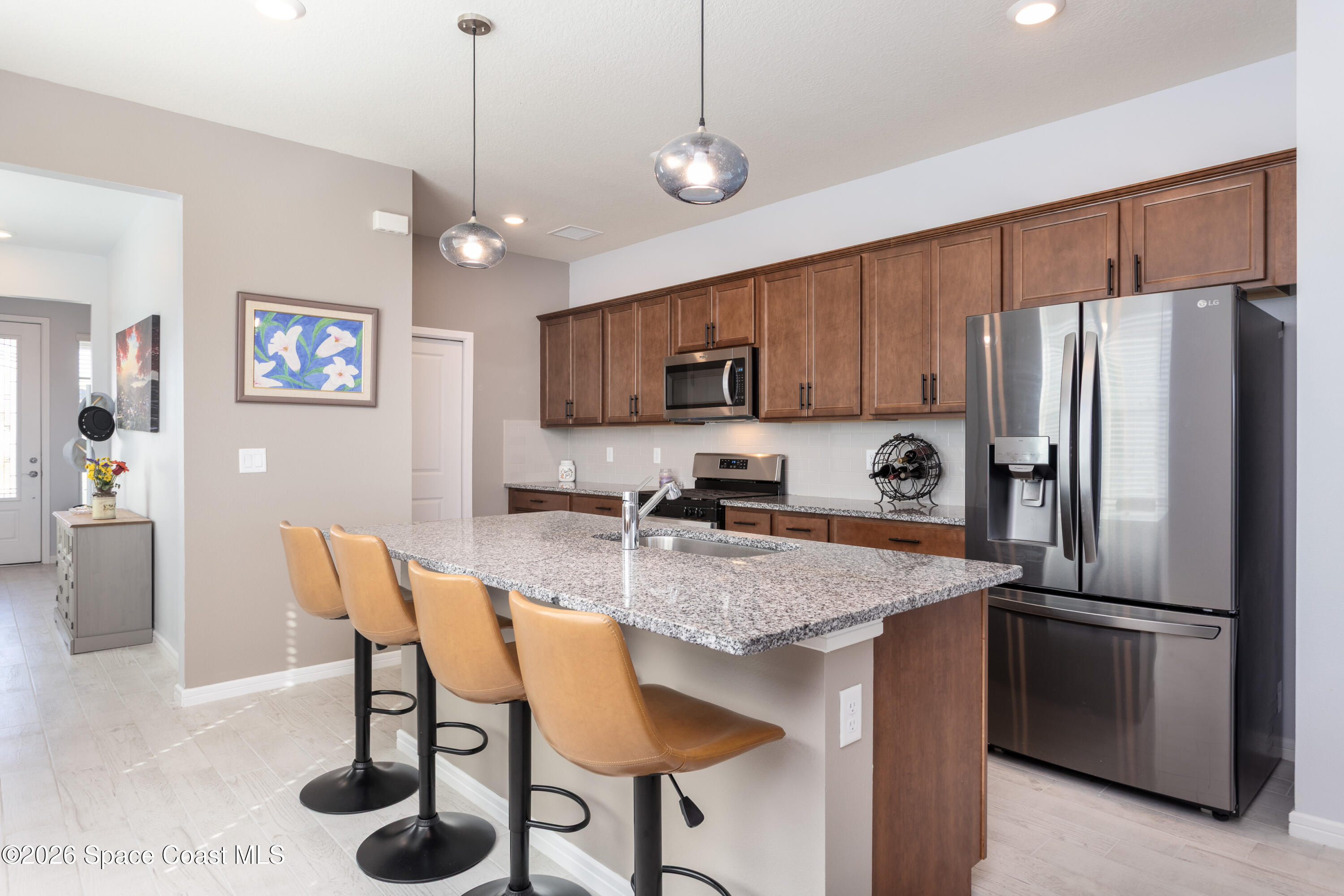 2993 Tidepool Place Melbourne, FL 32940 - Photo 8 of 50 a kitchen with stainless steel appliances granite countertop a refrigerator a sink a stove a dining table and chairs
