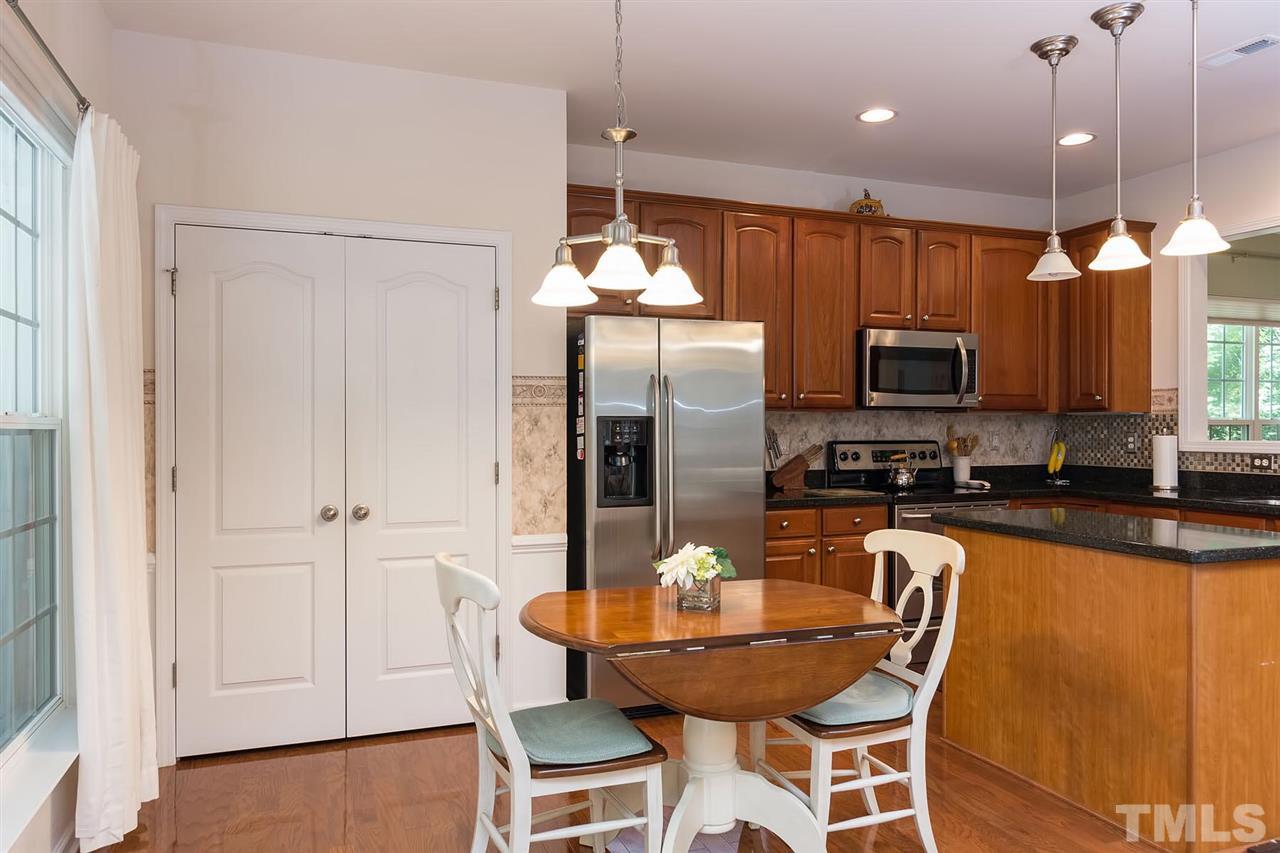 3413 Secretariat Way Raleigh, NC 27614 - Photo 7 of 23 a kitchen with granite countertop a refrigerator a stove a sink dishwasher a dining table and chairs with wooden floor