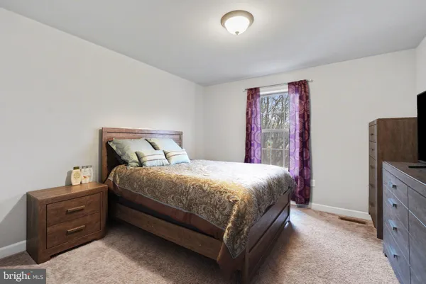 a bedroom with a bed and a flat tv screen on dresser
