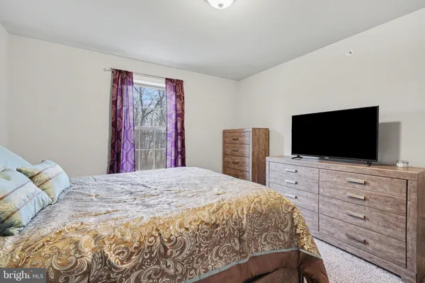 a bedroom with a bed and a flat screen tv in white walls