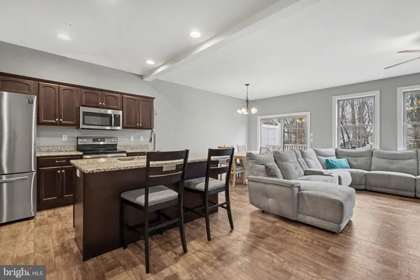 a living room with stainless steel appliances granite countertop furniture a fireplace a flat screen tv and a window