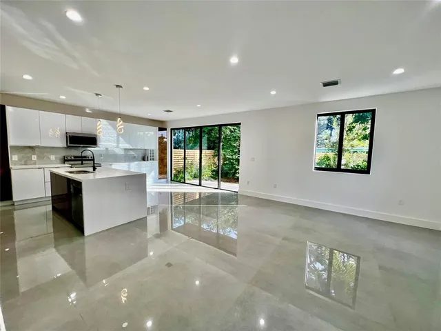 a large white kitchen with stainless steel appliances granite countertop a large counter top and a stove top oven