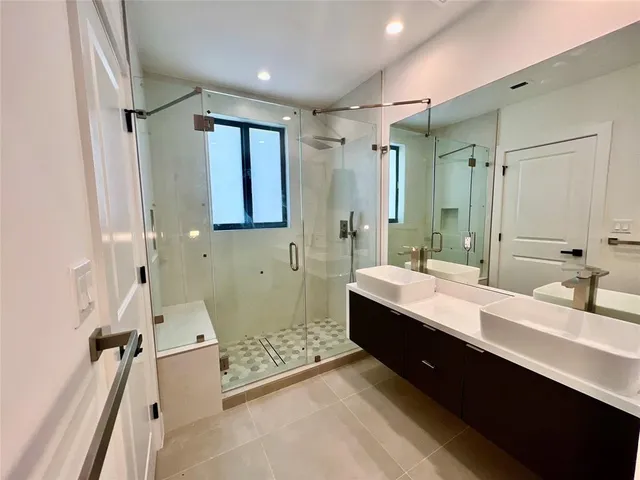 a bathroom with a double vanity sink mirror and shower