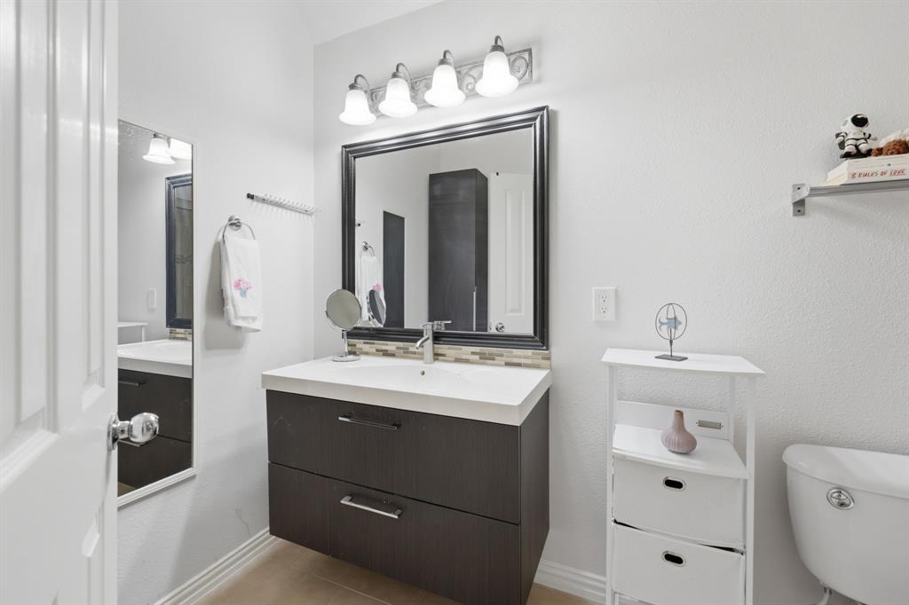 3315 Ricci Lane Irving, TX 75062 - Photo 31 of 40 Floating wood-finish vanity with an integrated sink, framed mirror, and a decorative tile backsplash