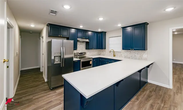 a kitchen with stainless steel appliances kitchen island granite countertop a refrigerator a sink and a stove