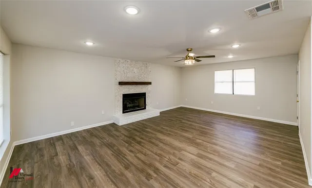 an empty room with a fireplace and wooden floor